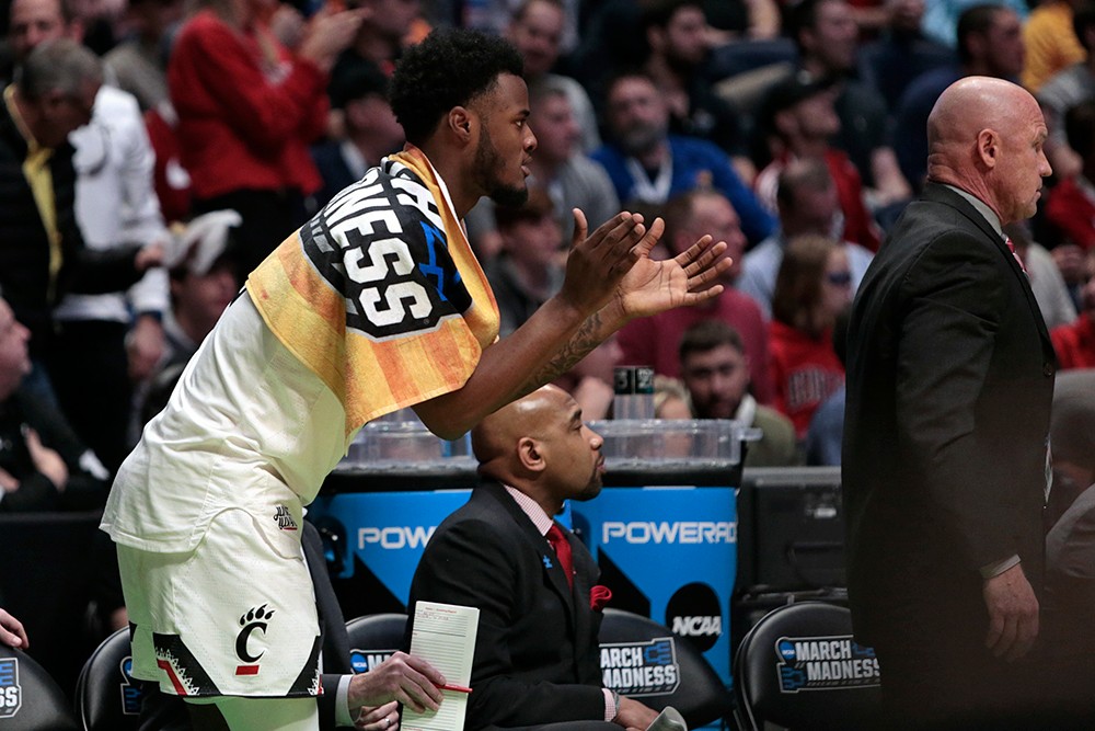 A UC player cheers on his teammates from the bench. 