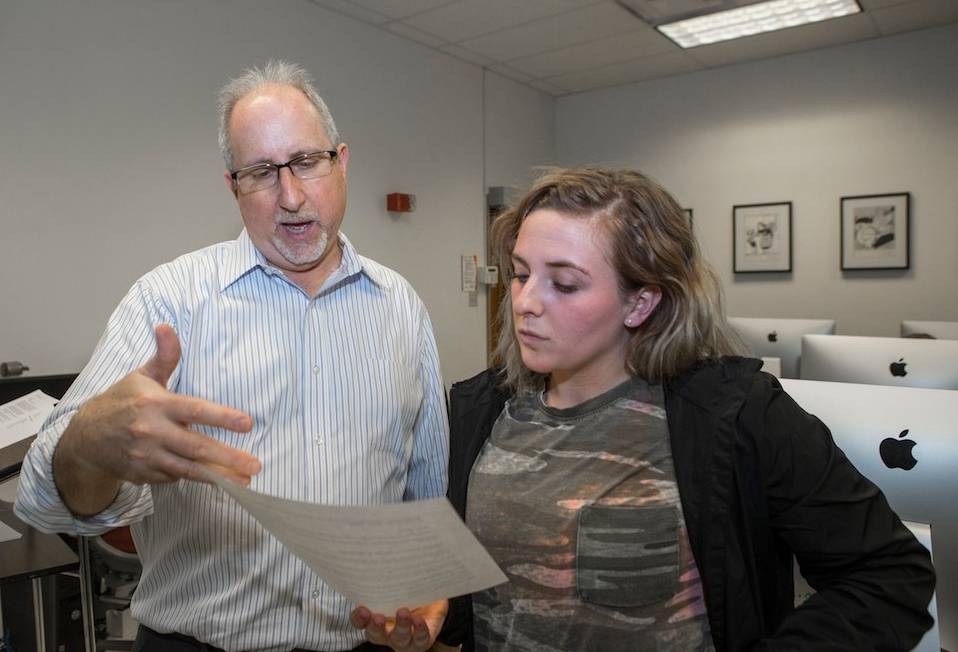 Michael Perry works with a UC journalism student in the classroom.