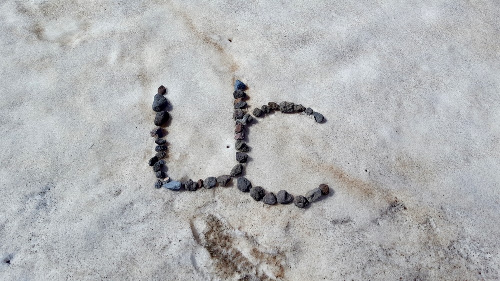 The initials for UC are created out of volcanic rock on the snowy surface of an alpine glacier.