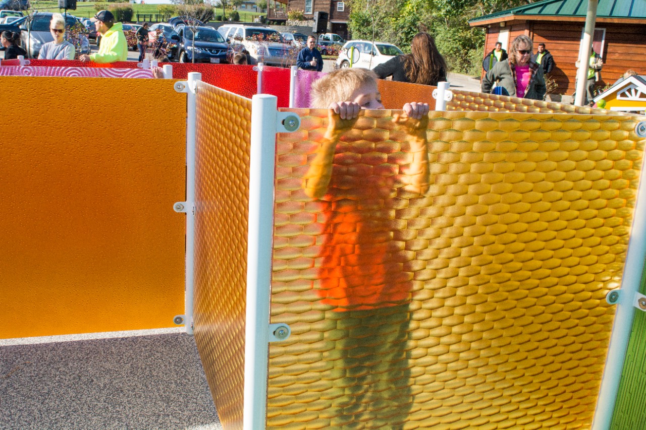 A child peeks over the top of a colored panel in the maze. 