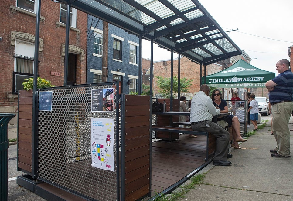 Photos/Andrew Higley/Creative Services Two people chat in the parklet, which features wood seating and tabletops.