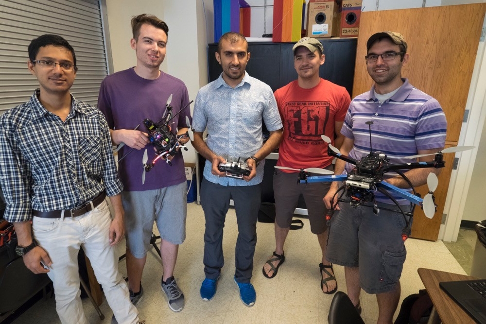 UC aerospace engineering students stand together holding hand made drones.