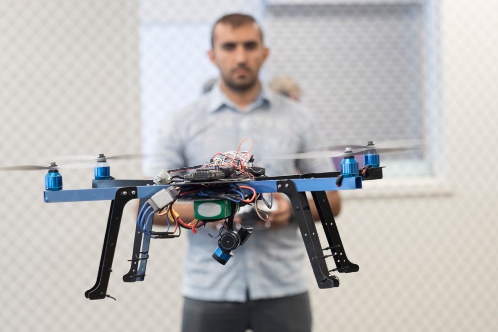 UC student operates a small drone in the air in front of him.