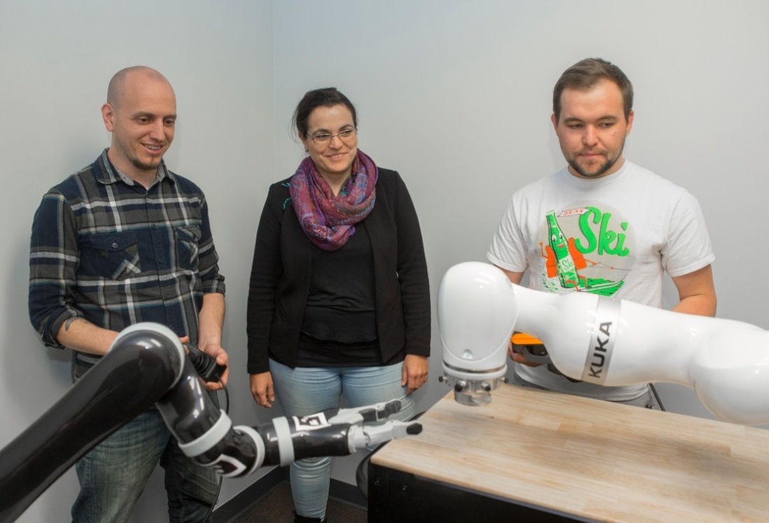UC postdoctoral fellow Maurice Lamb, left, assistant professor Tamara Lorenz and graduate student Riley Mayr work with robots in a psychology lab. 