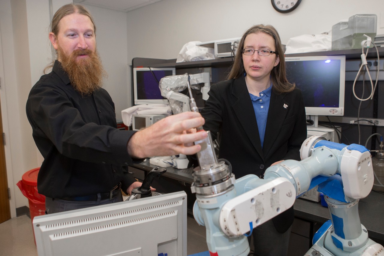 UC graduate student Christopher Korte, left, and Catharine McGhan, an assistant professor of aerospace engineering, are working with UC Health on a robot that can cut open the human skull for surgical procedures. 