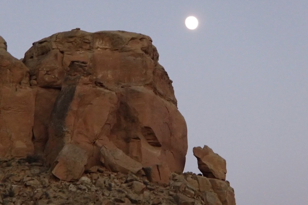Rocky boulder on a cliff with a lunar eclipse in the sky in Chaco Canyon, New Mexico.