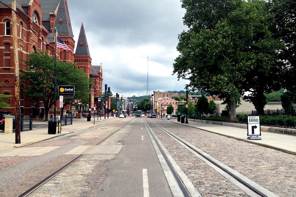 Old vs. New. On the left, the state of disrepair of the cobblestone roadway on Elm Street after decades of use in front of Music Hall. The section on the right was rehabilitated by Prus Construction during installation of the streetcar track. The historic pavers were removed, cleaned, then fitted back into place. (July 3, 2014)