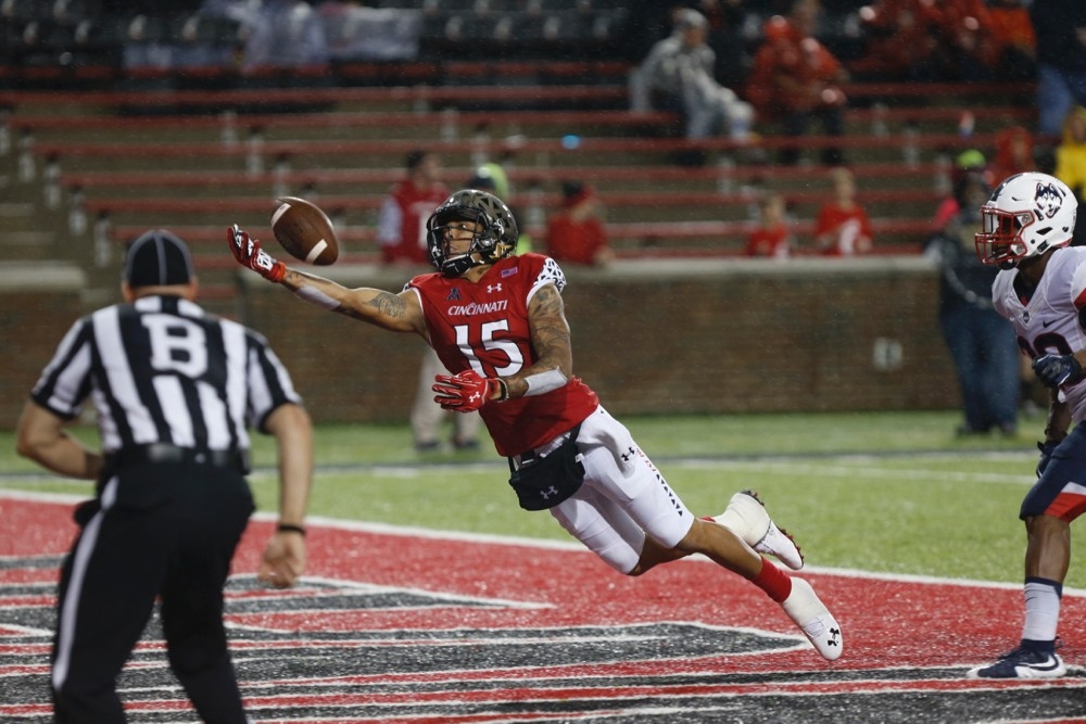 UC Bearcat football player wearing the Under Armour UC logo reaches for the ball during a game