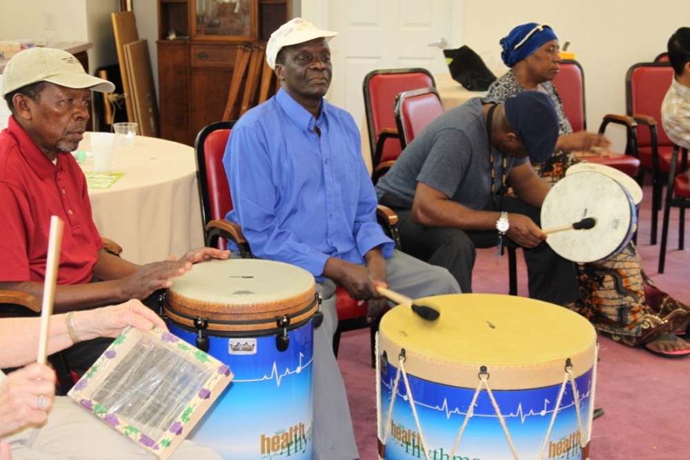 Refugees in the Maple Knoll nursing home play drums during UC Serves Day.
