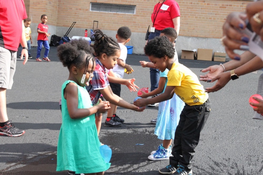 Children from the Rising Star Academy pass water balloons to each other.