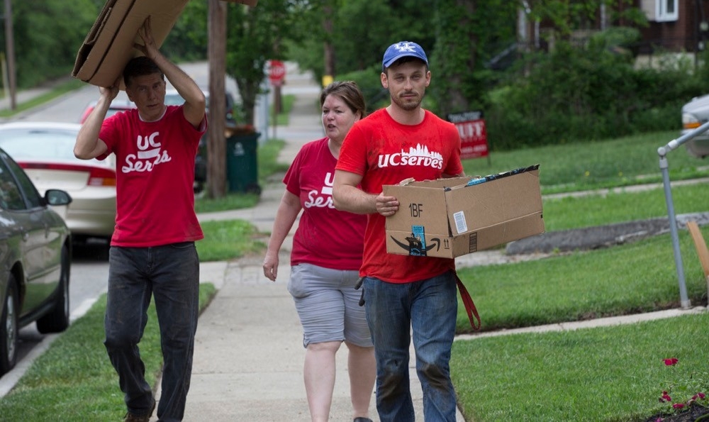 UC Serves volunteers carry boxes of supplies down an urban street on UC Serves Day. photo/Joseph Fuqua II/UC Creative Services