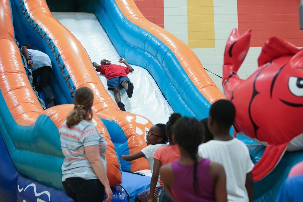 Children from Woodford Paideia Elementary School slide down an inflatable slide at UC Serves field day.