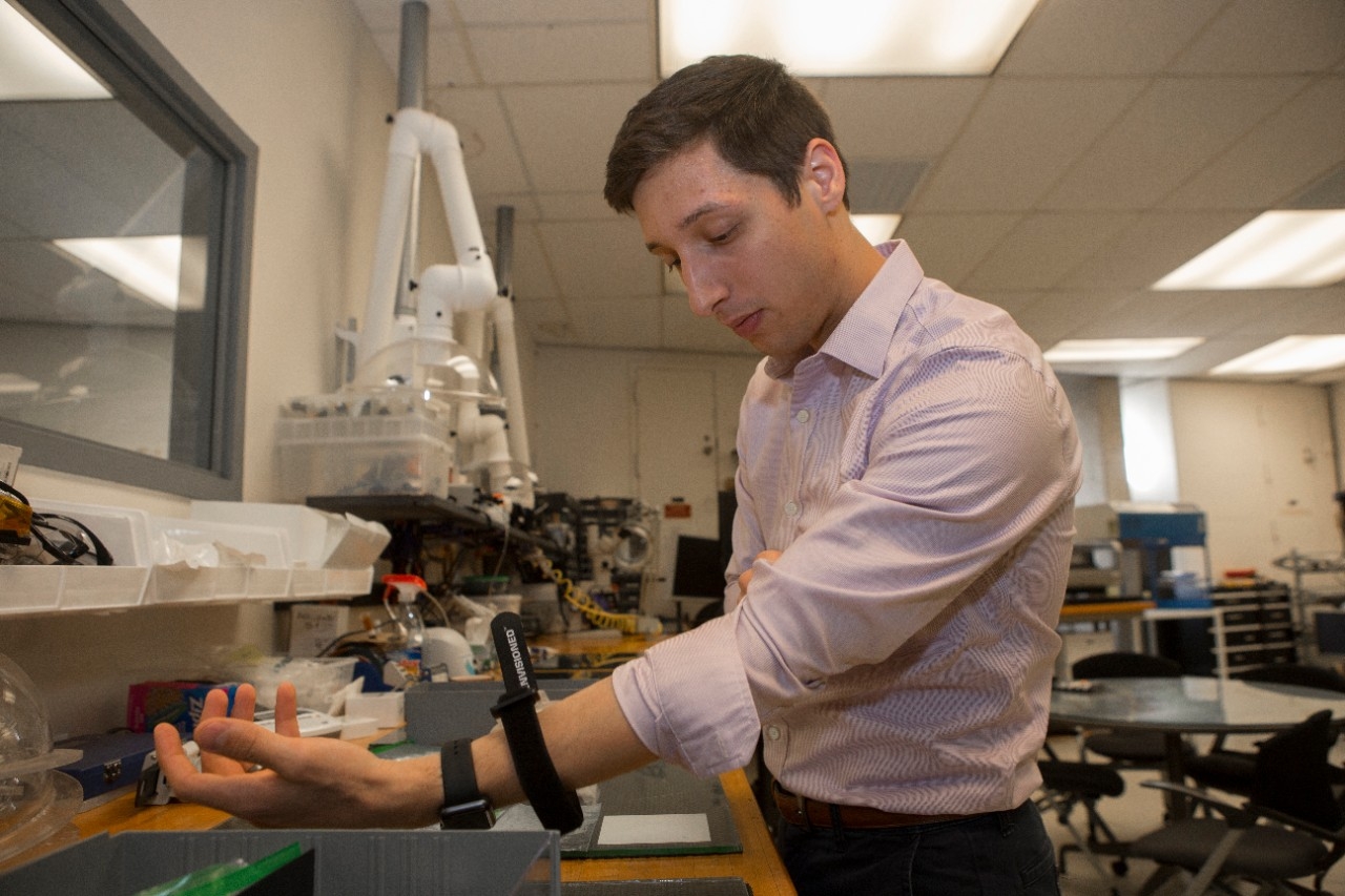 UC student Andrew Jajack demonstrates how a sweat sensor is applied to the skin in the Novel Devices Lab.