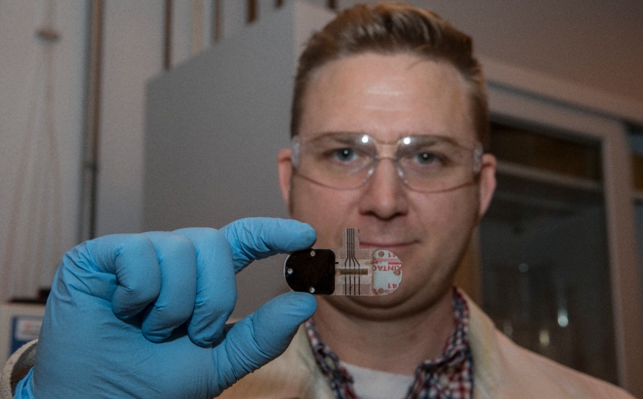 UC student Adam Hauke holds up the latest generation of sweat sensor in the Novel Devices Lab. 