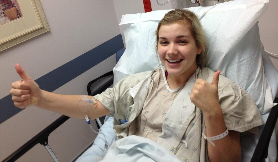 Sara Whitestone gives two thumbs up from a hospital bed