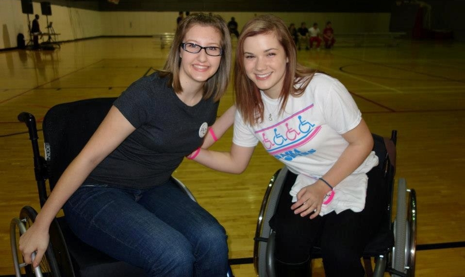Abbey Hunter and Sara Whitestone pose for a photo in their wheelchairs inside the Campus Recreation Center gymnasium.