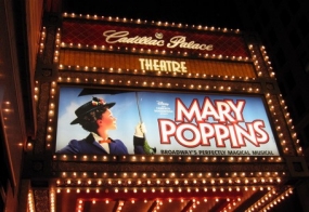 The Disney theater lit up at night with the Mary Poppins sign lit up, too.