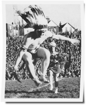 Drum major Don Poynter swings a sharp knife under his feet while dressed as an Indian.. 