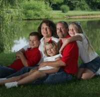 The Bryd family, father, mother and three children, relaxes next to a lake.