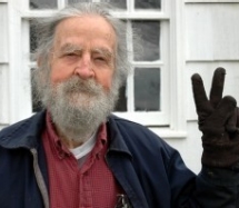 Gray-haired and bearded Gordon Maham flashes the peace sign with his fingers.