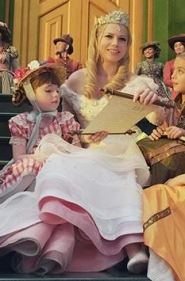 Glinda sitting on steps reading to children