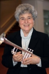 Marie Speziale smiles into the camera while holding her trombone.