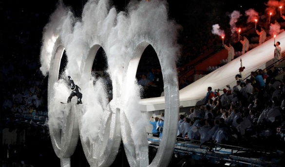 A sled rider shoots through a display of the Olympic interlocking circles.