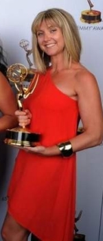 Cara Hannah Sullivan poses for a photo holding the Emmy she won. She is quite an attractive women in a stylish red evening dress and blonde hair.