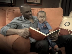 Rodney Van Johnson reading a book to toddler Joshua.