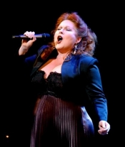 Kim Criswell singing into a microphone, wearing an evening dress.