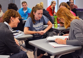 Some members of the University of Cincinnati Foundation board meet with students in a classroom.