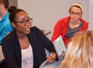 A member of the University of Cincinnati Foundation board sits in a classroom talking to students about their day-to-day lives.