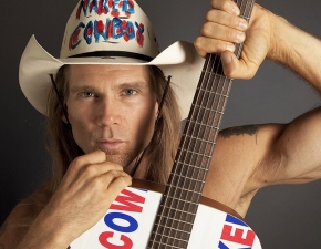 A photo of a man with a cowboy hat and holding up a guitar is University of Cincinnati alum Robert Burck, better known as the Naked Cowboy.