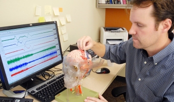 UC researcher Jed Hartings examines a model of the human brain.