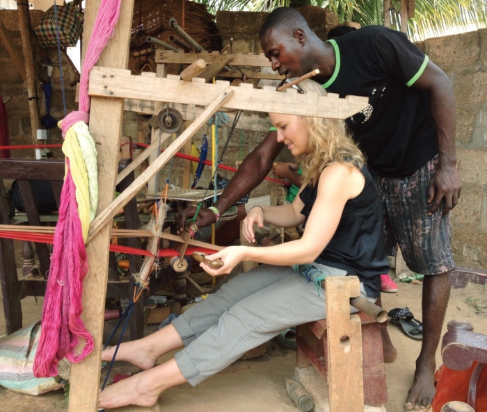 UC alumna Natalie Bullock, Bus ’15, receives a lesson in weaving traditional Kente cloth during a trip to Ghana.