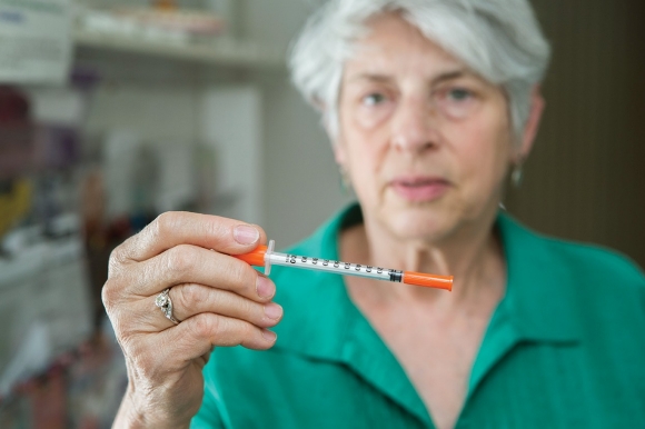 Dr. Judith Feinberg, a University of Cincinnati physician, holds a syringe.