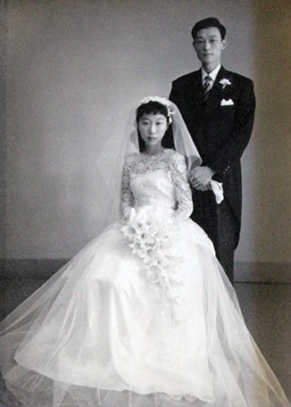 A black-and-white wedding photo with a bride seated and the groom standing behind. It shows UC President Santa Ono's parents, Takashi and Sachiko Ono, on their wedding day.