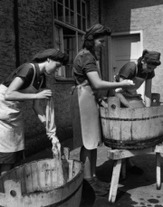 Three young women wash clothes by hand.