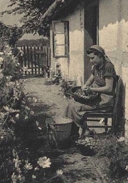 Young woman sits in the yard peeling potatoes.