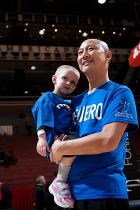 UC President Santa Ono holds Katie, a young cancer patient, soon after having his head shaved in front of thousands at UC's Fifth Third Arena in January 2013 to help raise funds for the Dragonfly Foundation. photo/Ashley Kempher