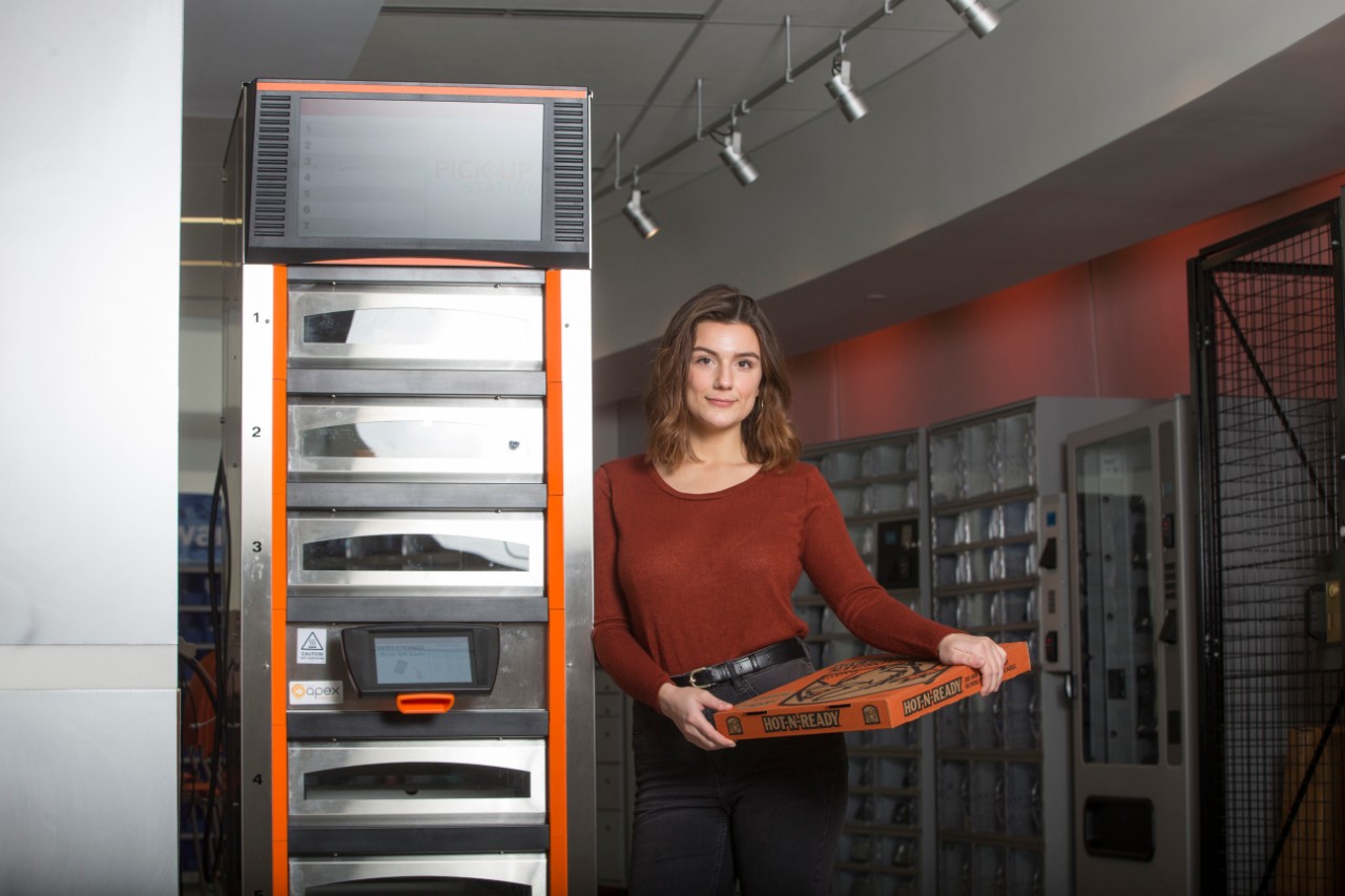 DAAP co-op student Maggie Otten holds a pizza box inside a LIttle Caesars