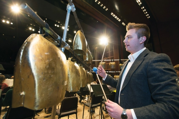 A percussionists stands ready to play a set of huge alpine bells (or tuned cowbells) during a performance at the University of Cincinnati.