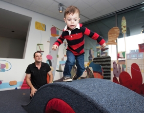 A youngster toddles his way over a carpeted bridge inside the Contemporary Arts Center.