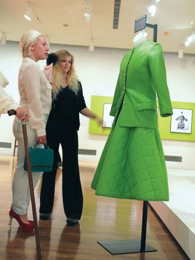 Two women admire a lime-green separates suit in an art gallery, part of the Bonnie Cashin collection house at UC.