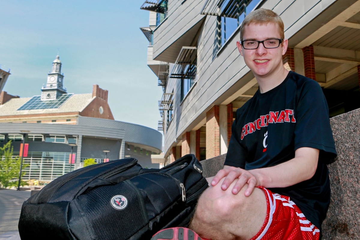 Dustin Stein sits on granite seating along UC's MainStreet. 