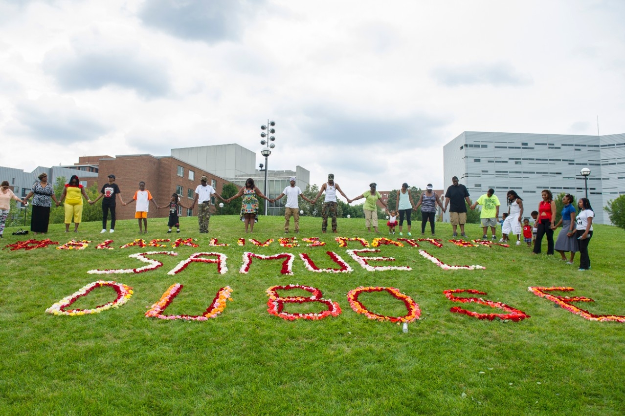  Family and friends of Samuel DuBose hold hands around a rose memorial as part of a remembrance on campus Aug. 9, 2015.