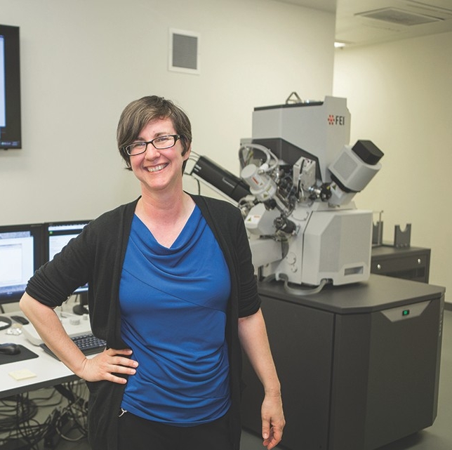 Melodie Fickenscherstands next to the dual-beam microscope