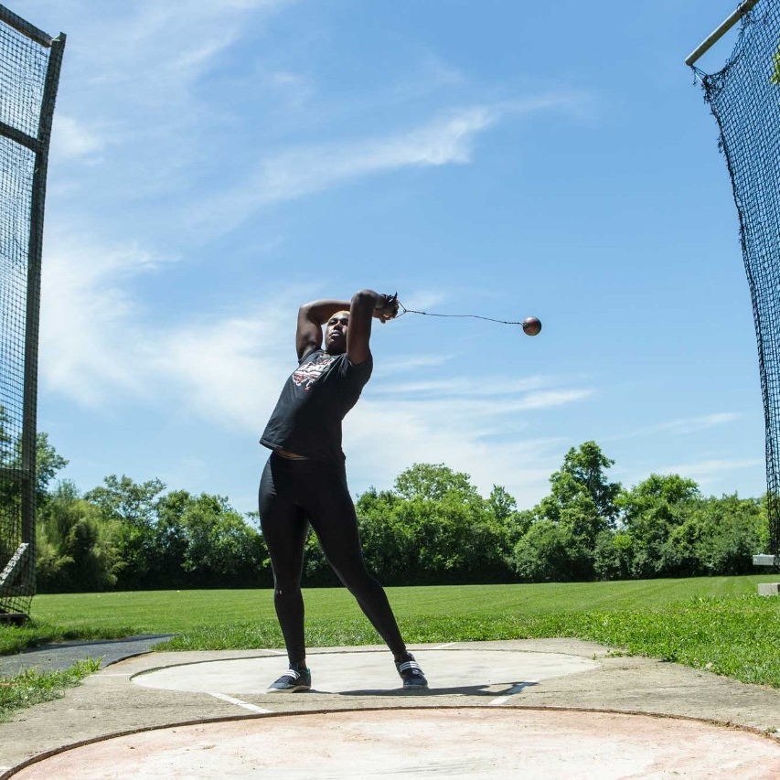 Echikunwoke demonstrates a hammer throw outdoors at Coy Field near UC's campus (1 of 3)