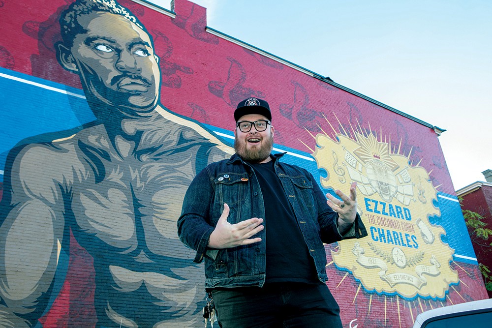 A University of Cincinnati alumnus and artist, Jason Snell, stands in front of his large mural of boxer Ezzard Charles.