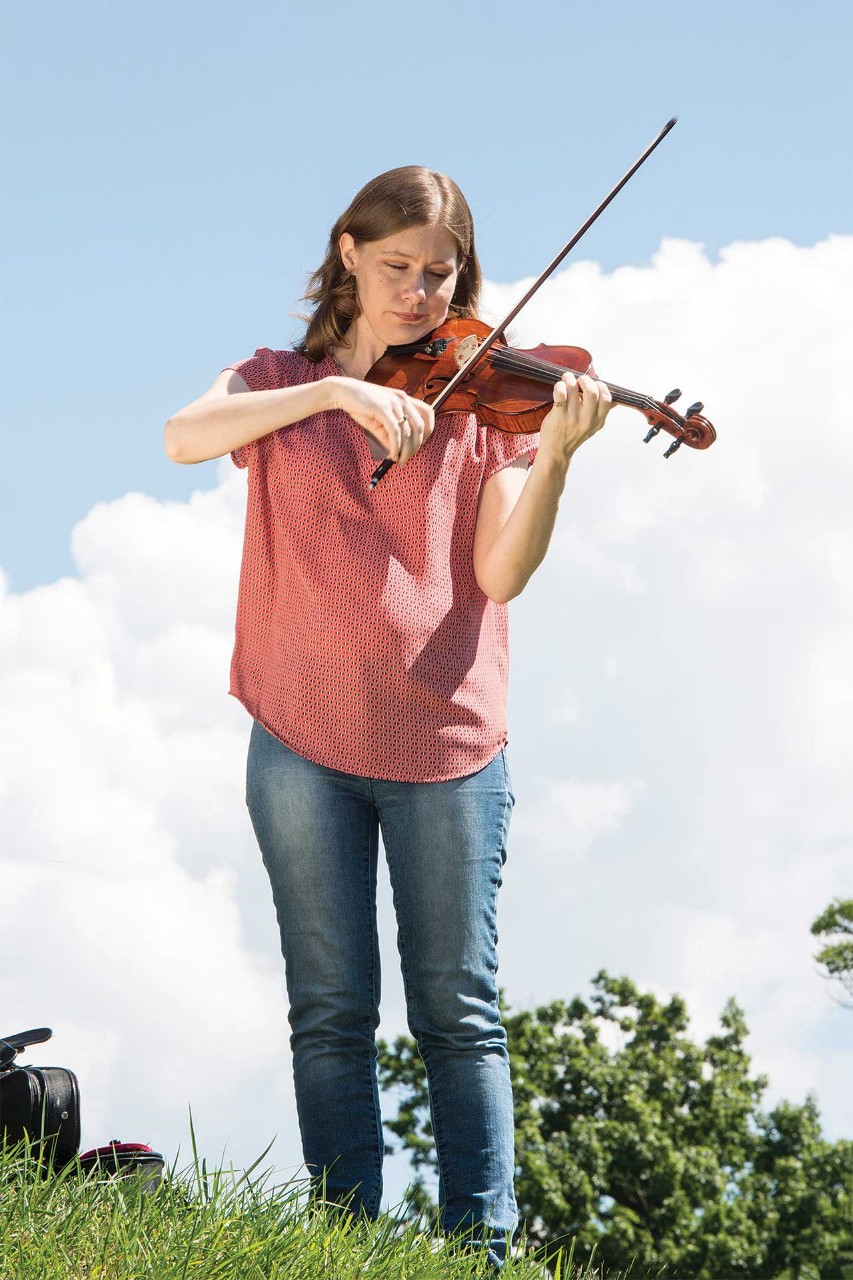 Bethany Yeiser standing outside on campus playing violin